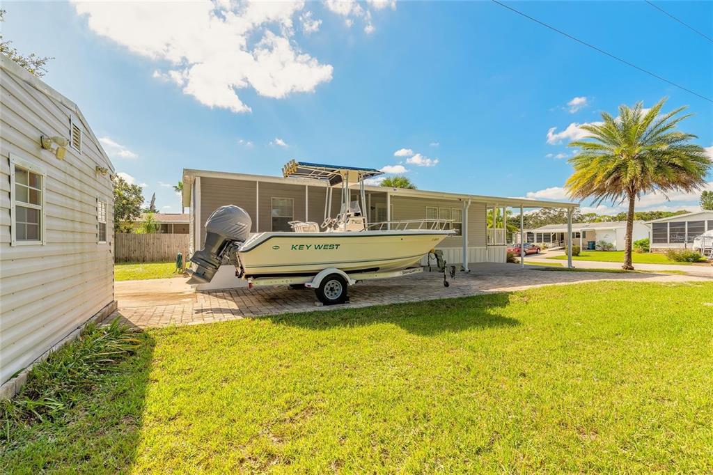 A boat on a trailer is parked on a paved driveway beside a residential home — 152 RED BASS LANE, EDGEWATER, FL
