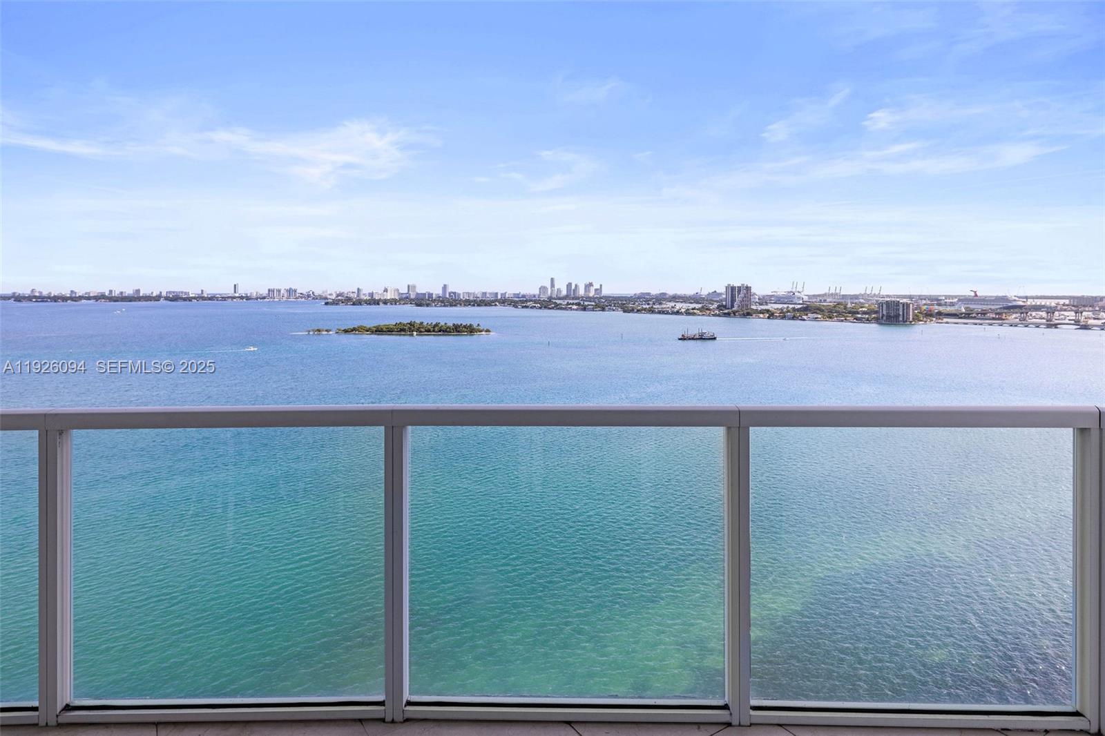 A view of the ocean and distant city skyline from a glass-railed balcony — 665 NE 25th St # 1801, Miami FL 33137, MIAMI, FL