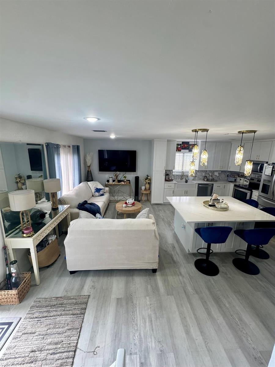 An open-concept living room and kitchen featuring light wood-look flooring and a white island — 4631 Cherry Road, West Palm Beach FL 33417, WEST PALM BEACH, FL