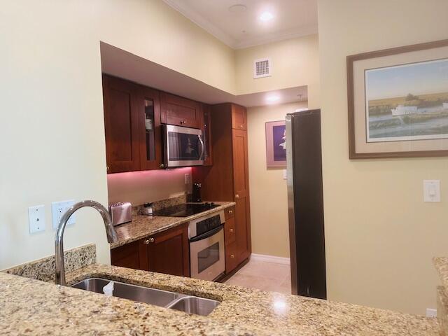 A kitchen features cherry wood cabinets, granite countertops, stainless steel appliances, and a double sink — 975 NW Flagler Avenue # 403, Stuart FL 34994, STUART, FL