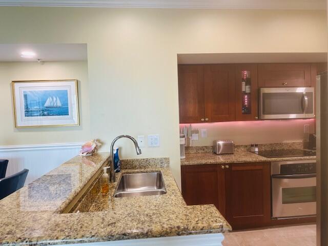 A kitchen features wood cabinets, granite countertops, a stainless steel sink, and a microwave — 975 NW Flagler Avenue # 403, Stuart FL 34994, STUART, FL