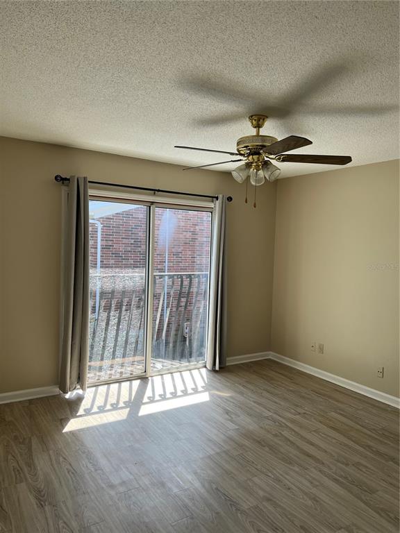 A bedroom with light wood-look flooring, a ceiling fan, and sliding glass doors to a balcony — 2200 S PALMETTO AVENUE UNIT D030, DAYTONA BEACH, FL