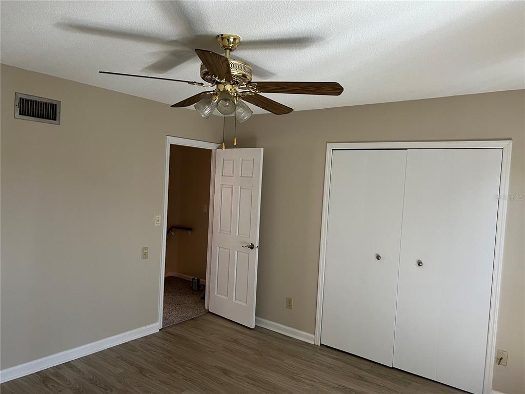 A bedroom features light-colored walls, wood-look flooring, a ceiling fan, and a white closet — 2200 S PALMETTO AVENUE UNIT D030, DAYTONA BEACH, FL