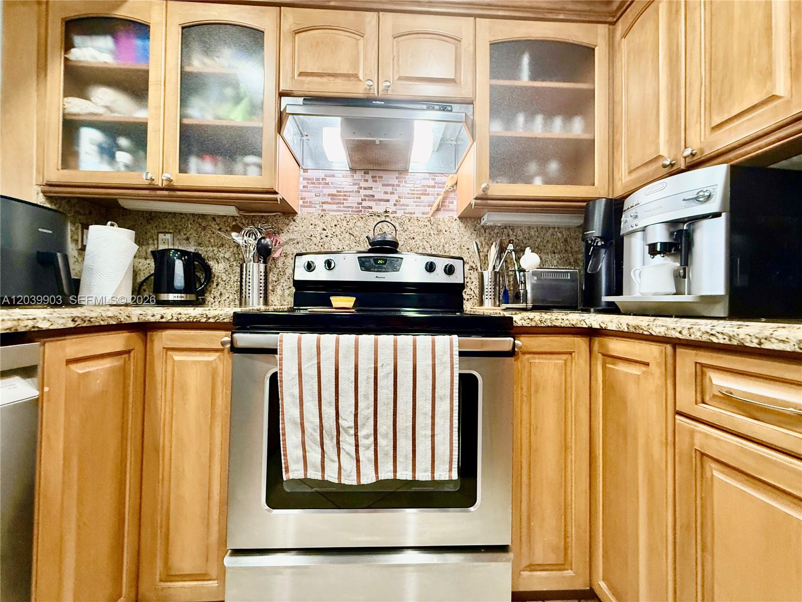 A kitchen features wood cabinets, stainless steel appliances, and a granite countertop — 500 Three Islands Blvd # 421, Hallandale Beach FL 33009, HALLANDALE BEACH, FL