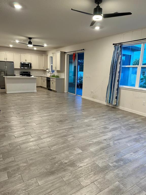 An open-concept kitchen and living area features light gray wood-look tile flooring and ceiling fans — 772 PARSONS MOORING COURT, SEFFNER, FL