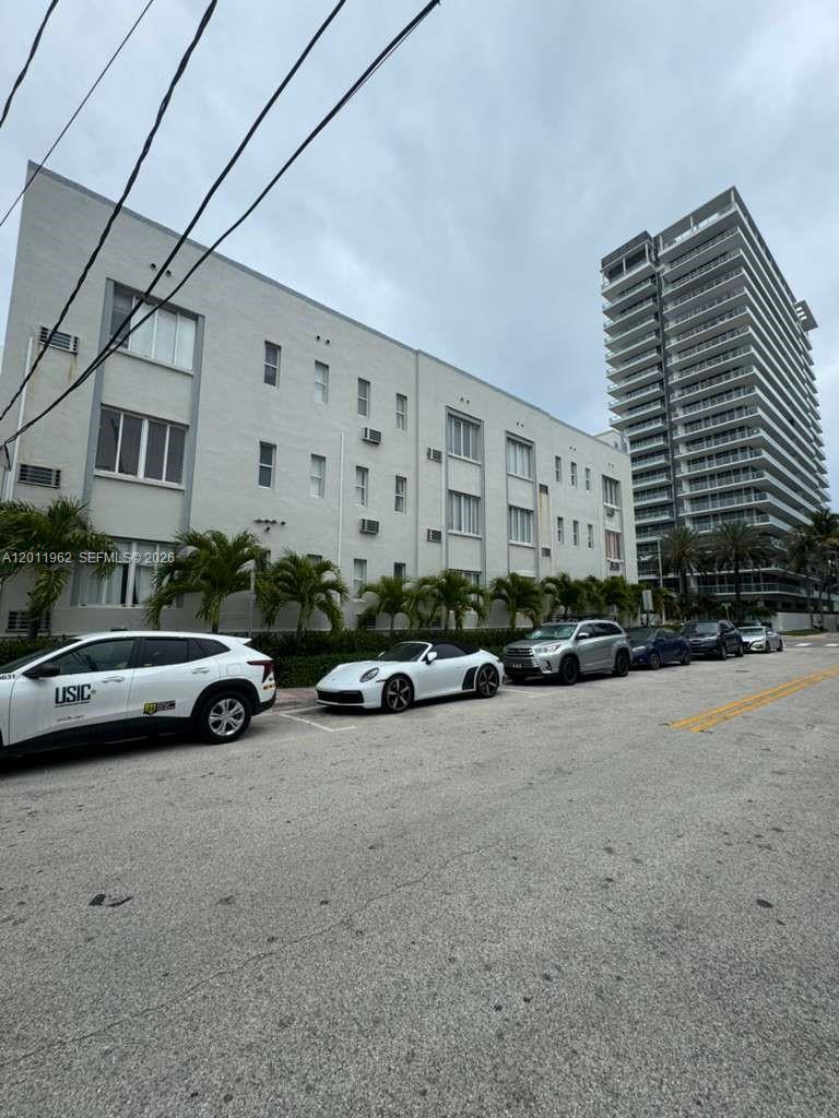 A low-rise apartment building stands next to a modern high-rise with parked cars in front — 3700 Collins Ave # 309, Miami Beach FL 33140, MIAMI BEACH, FL