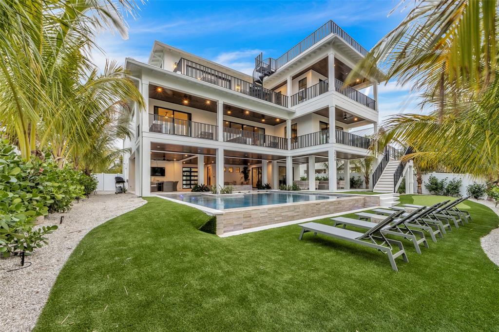 A three-story white house with a swimming pool, artificial turf, and multiple balconies — 224 CHILSON AVENUE, ANNA MARIA, FL