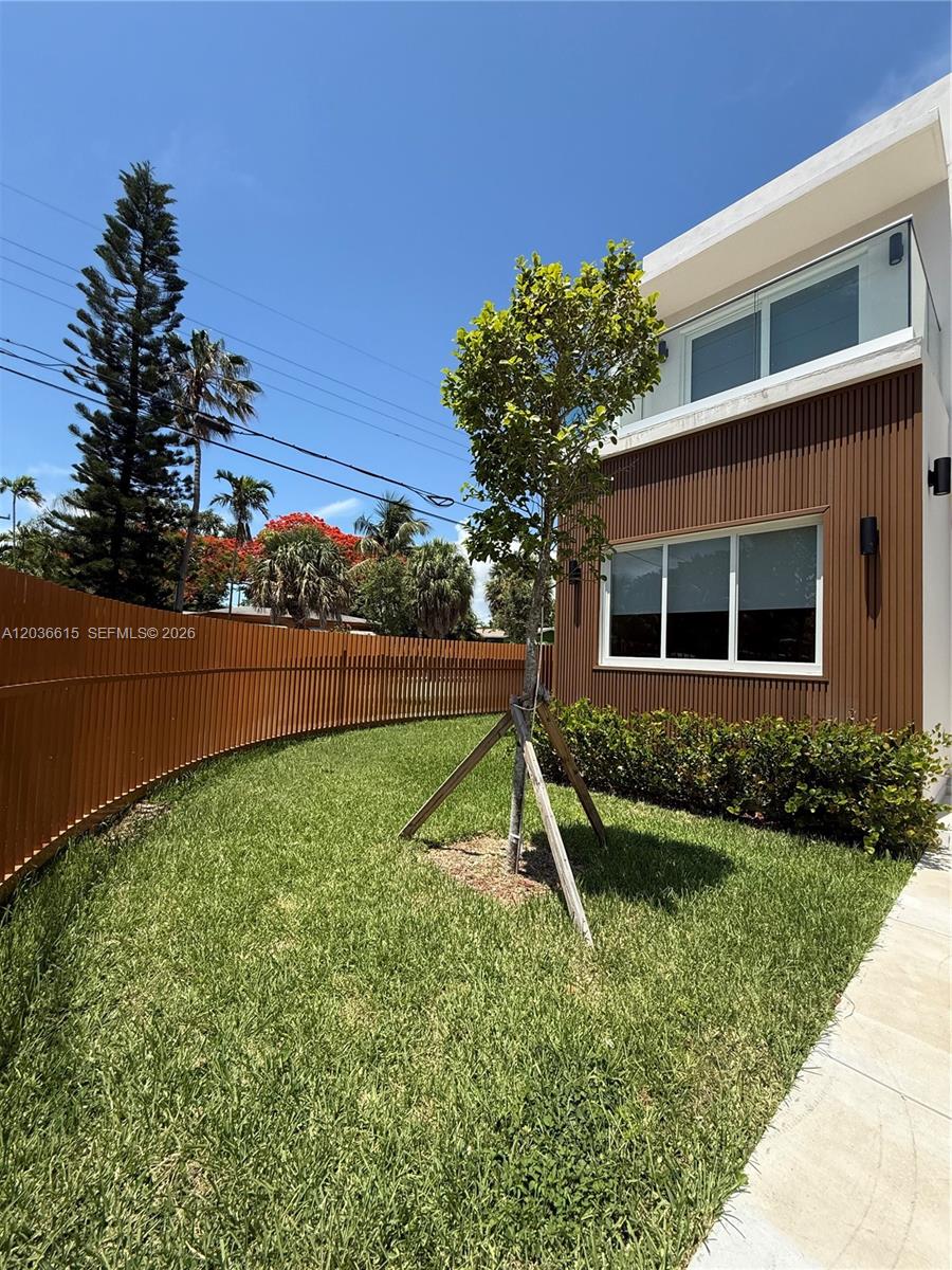 A modern house exterior features brown vertical siding, a glass balcony, and a fenced yard — 3326 Elizabeth St, Miami FL 33133, MIAMI, FL