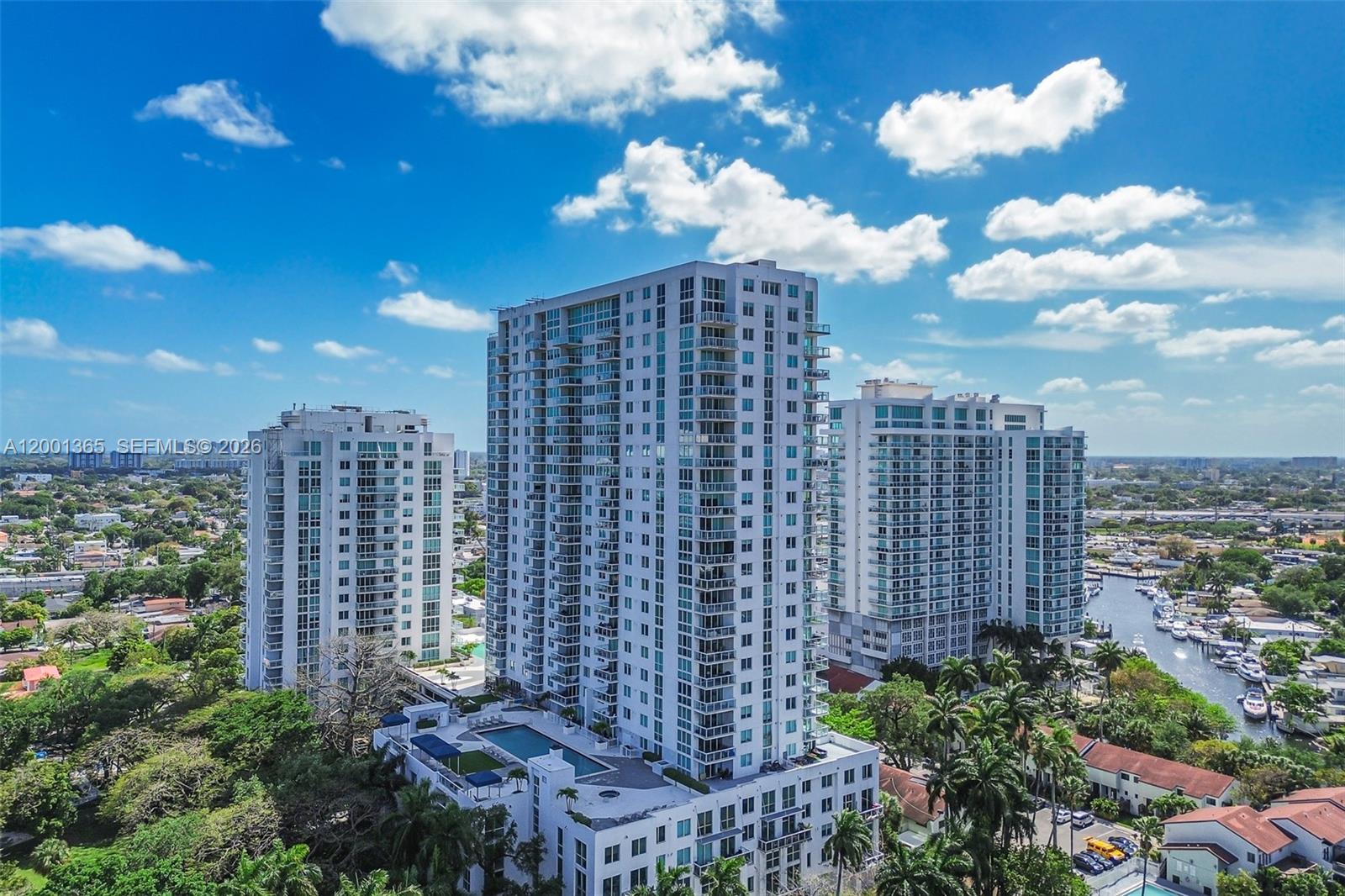 An aerial view shows three tall residential apartment buildings surrounded by trees and a canal — 1861 NW S River Dr # 2006, Miami FL 33125, MIAMI, FL