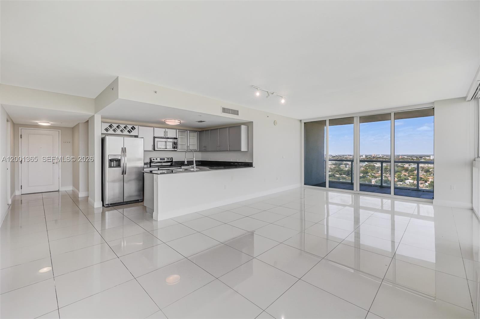 An open-concept kitchen with stainless steel appliances overlooks a bright living area with tile floors — 1861 NW S River Dr # 2006, Miami FL 33125, MIAMI, FL
