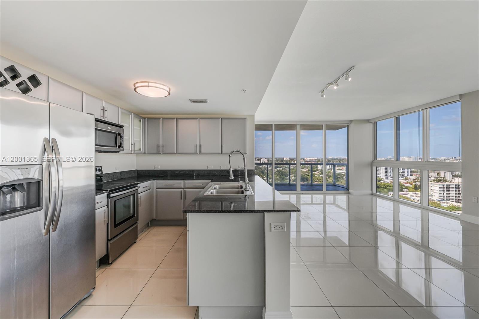 A modern kitchen with stainless steel appliances and granite countertops overlooks a balcony with views — 1861 NW S River Dr # 2006, Miami FL 33125, MIAMI, FL
