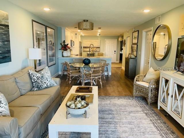 A living room with a beige sofa, white coffee table, and an open kitchen beyond — 113 1ST STREET E UNIT 103, TIERRA VERDE, FL