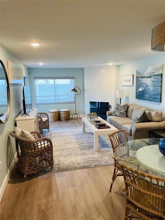 A living room features a fireplace, wicker furniture, a sofa, and a view of the ocean — 113 1ST STREET E UNIT 103, TIERRA VERDE, FL