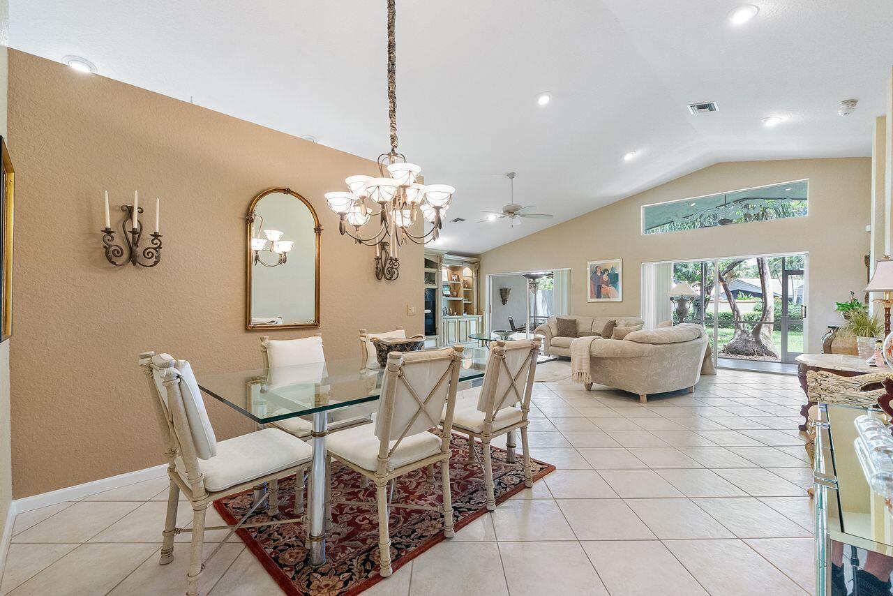A dining area with a glass table and chandelier opens into a living room with tile floors — 6643 Sherbrook Drive, Boynton Beach FL 33437, BOYNTON BEACH, FL