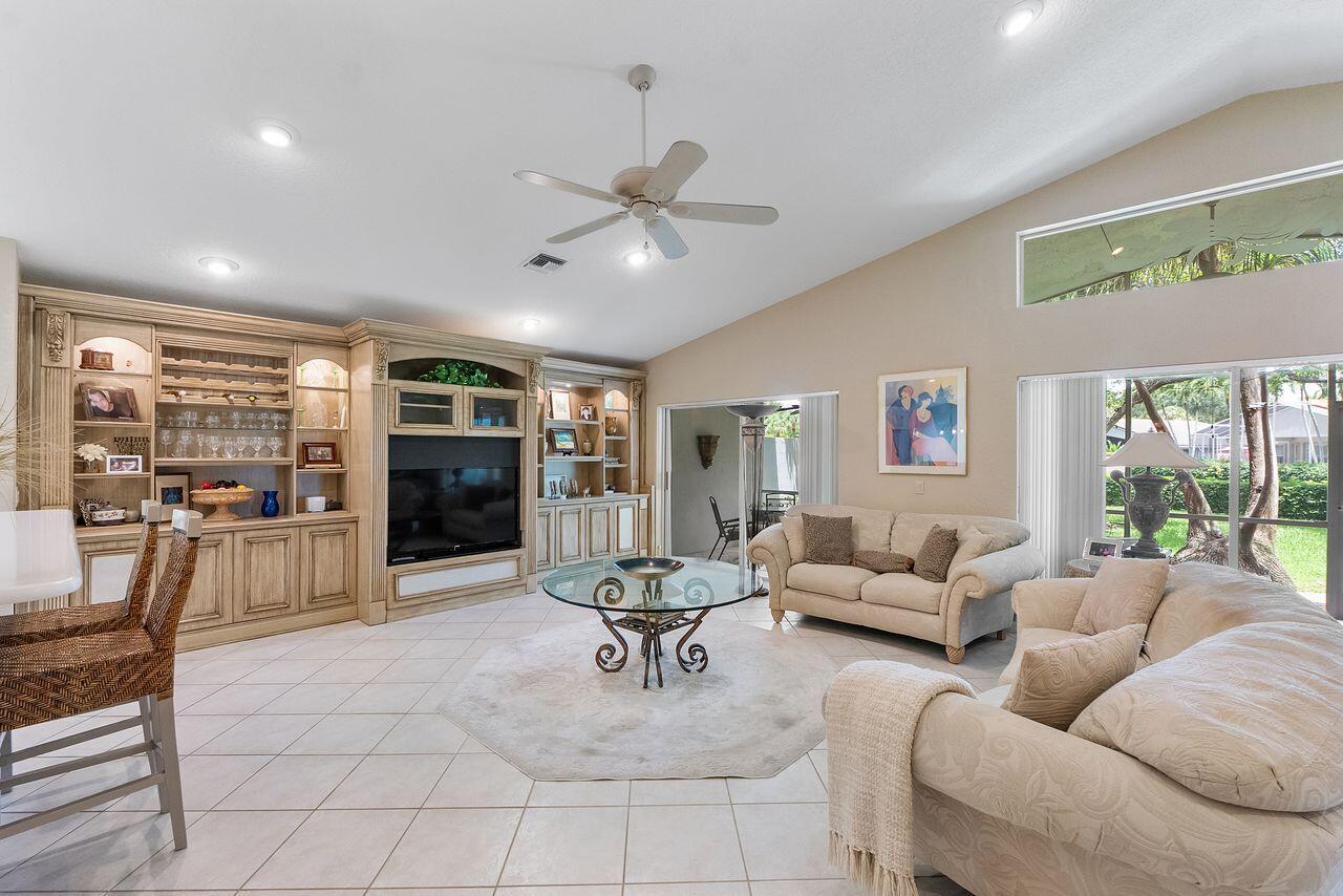 A living room features a large built-in entertainment center, tile flooring, and a vaulted ceiling — 6643 Sherbrook Drive, Boynton Beach FL 33437, BOYNTON BEACH, FL