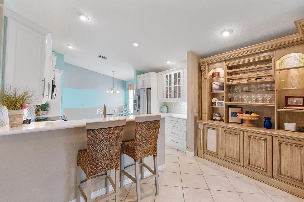 A kitchen features a breakfast bar with two woven stools and a large wooden hutch — 6643 Sherbrook Drive, Boynton Beach FL 33437, BOYNTON BEACH, FL