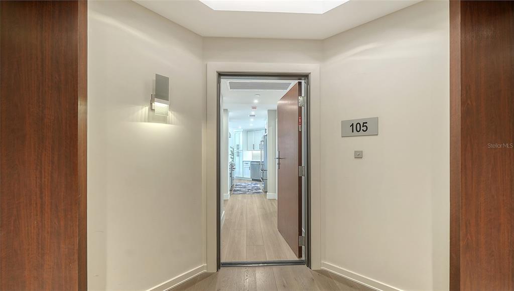 A view through an open doorway into a modern apartment hallway and kitchen — 1211 GULF OF MEXICO DRIVE UNIT 105, LONGBOAT KEY, FL