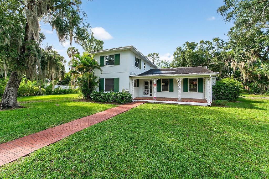 A two-story white house with green shutters and a brick walkway sits on a lawn — 5240 20th Street, Vero Beach FL 32966, VERO BEACH, FL