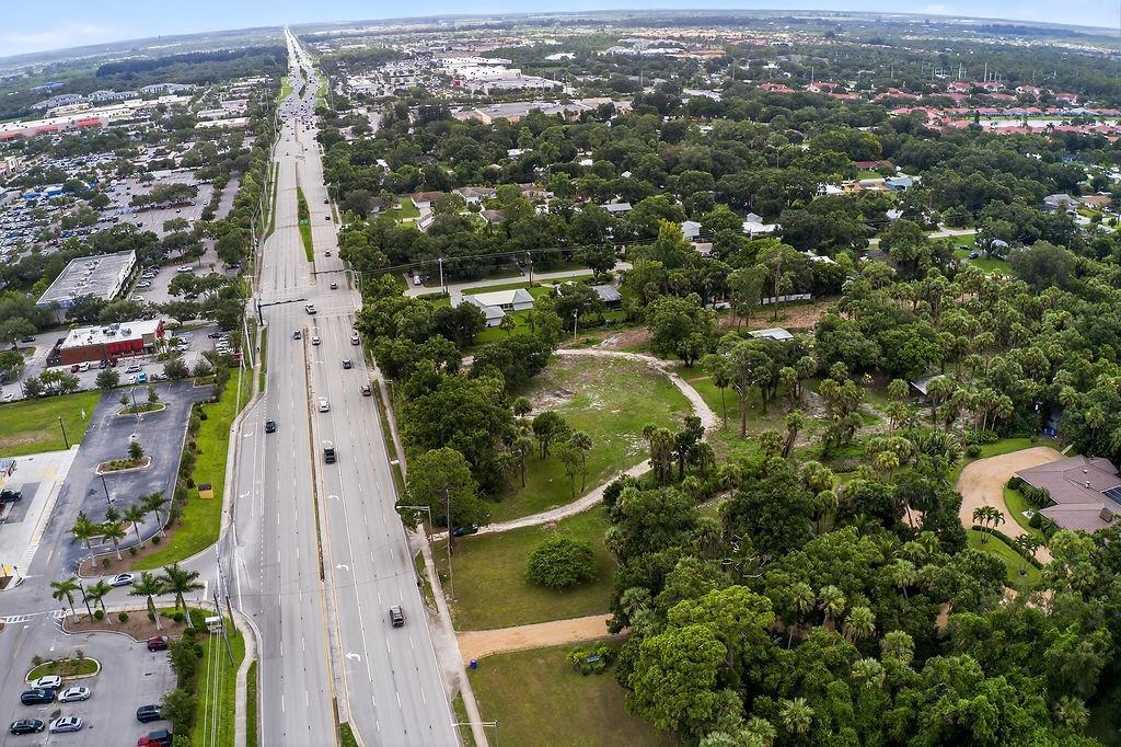 An aerial view shows a multi-lane road running alongside a wooded lot and suburban neighborhood — 5240 20th Street, Vero Beach FL 32966, VERO BEACH, FL