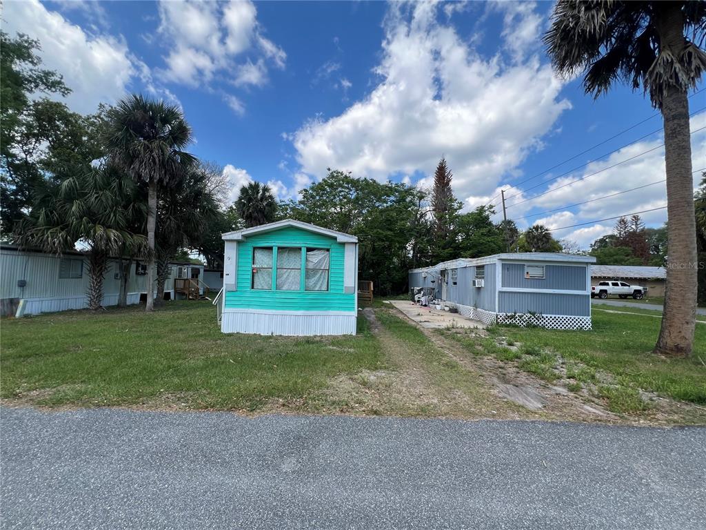 Two mobile homes sit on a grassy lot with palm trees under a cloudy sky — 30 WAFFORD STREET, UMATILLA, FL