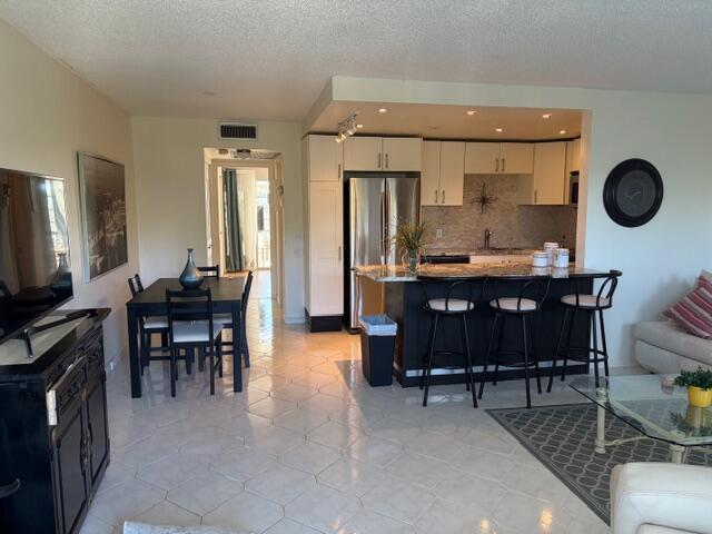 An open-concept kitchen with a breakfast bar, dining area, and living space with tile flooring — 4008 Birkshire A # 4008, Deerfield Beach FL 33442, DEERFIELD BEACH, FL