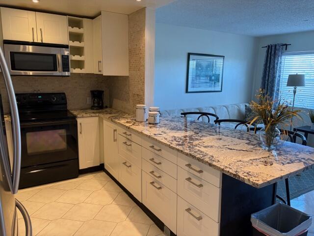 A kitchen features white cabinetry, granite countertops, a black stove, and a breakfast bar — 4008 Birkshire A # 4008, Deerfield Beach FL 33442, DEERFIELD BEACH, FL