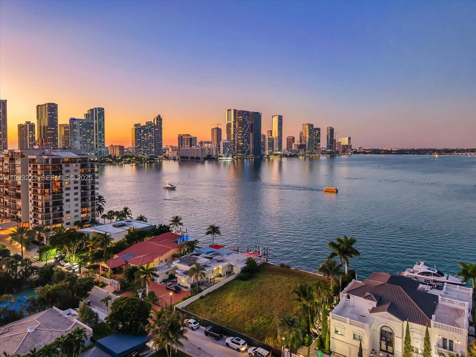 An aerial view shows a waterfront residential area with a city skyline in the background — 851 N Venetian Dr, Miami FL 33139, MIAMI, FL