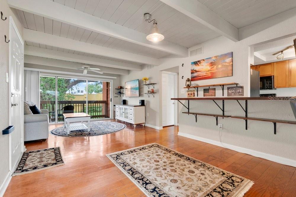 A living room with wood floors, exposed ceiling beams, a sliding glass door, and bar seating — 792 E MICHIGAN STREET UNIT 14, ORLANDO, FL