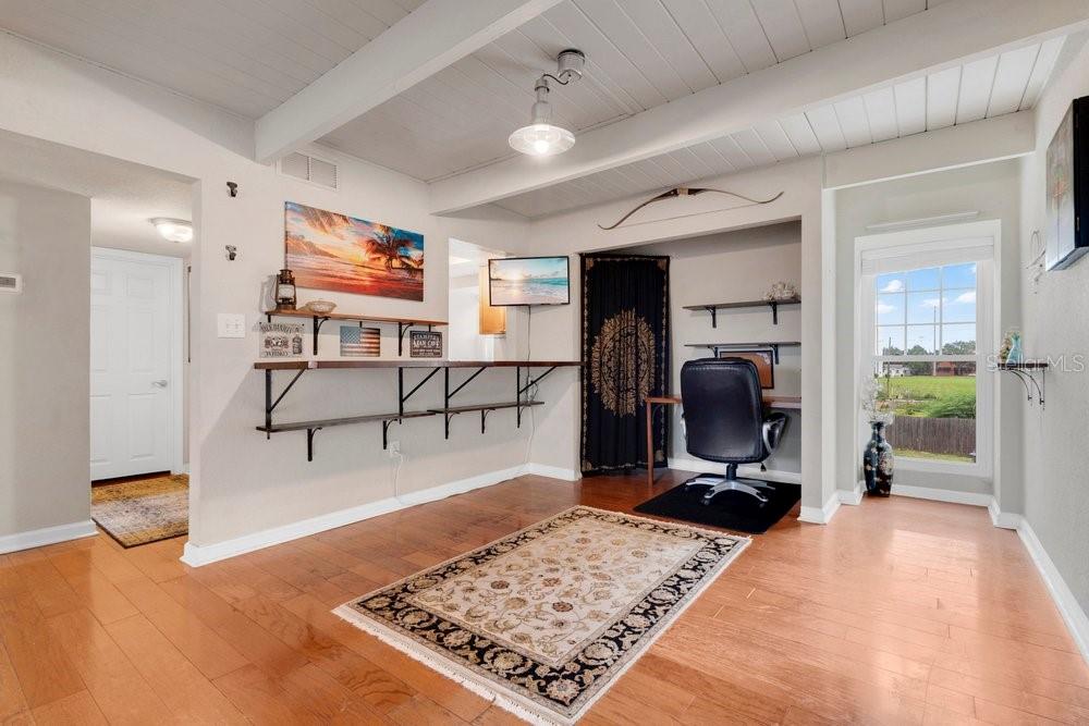 A room with hardwood floors, a wall-mounted desk, a workspace area, and a ceiling beam — 792 E MICHIGAN STREET UNIT 14, ORLANDO, FL
