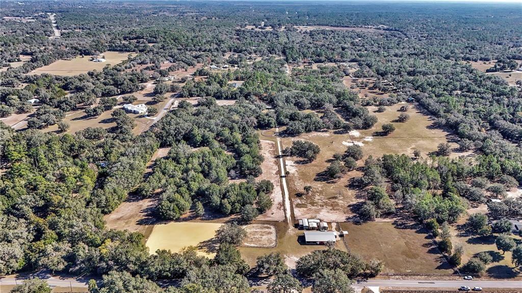 An aerial view shows a rural property with a barn, paddocks, and wooded acreage — 11375 N CIRCLE M AVENUE, DUNNELLON, FL