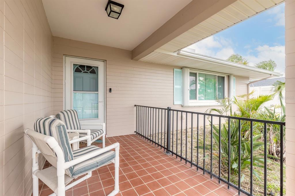 A covered porch features terracotta tile flooring, a black metal railing, and a white chair — 2315 BONNIE VIEW DRIVE, ORMOND BEACH, FL