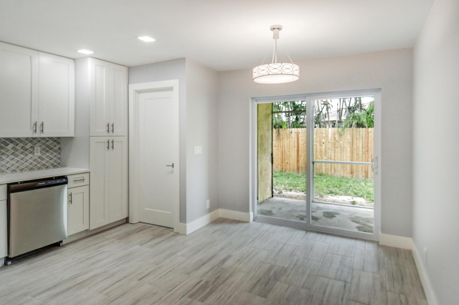 A kitchen and dining area with white cabinets, stainless steel appliances, and a sliding glass door — 9128 Roan Lane, West Palm Beach FL 33403, WEST PALM BEACH, FL