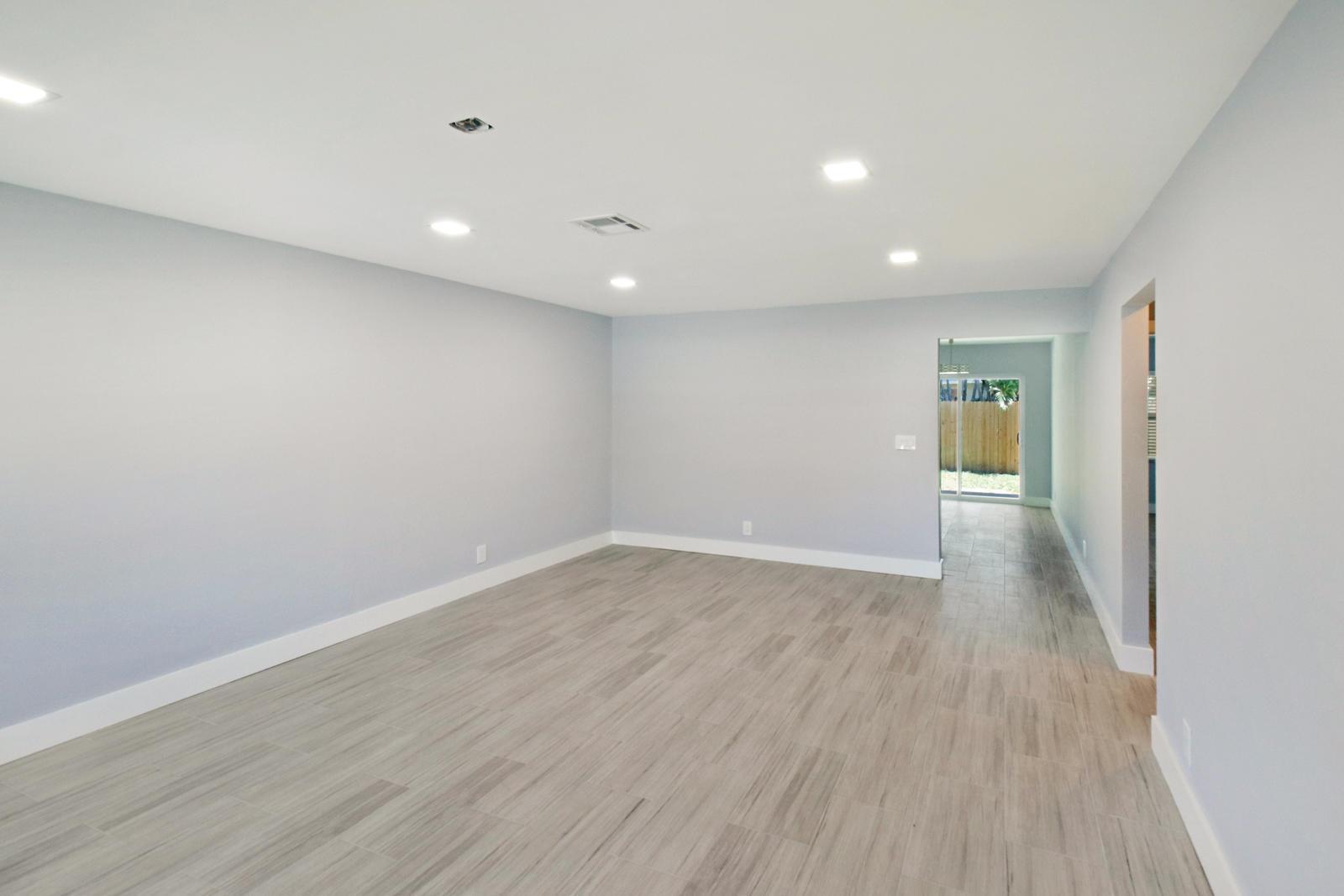 An empty room with light gray walls, wood-look tile flooring, and recessed ceiling lights — 9128 Roan Lane, West Palm Beach FL 33403, WEST PALM BEACH, FL