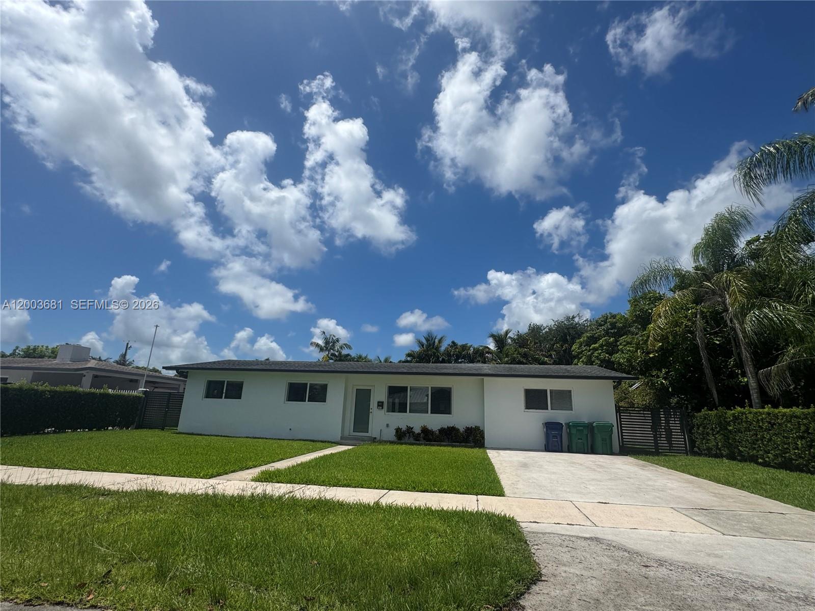 A single-story white house with a concrete driveway and a green lawn under blue skies — 8640 SW 125th Ter, Miami FL 33156, MIAMI, FL