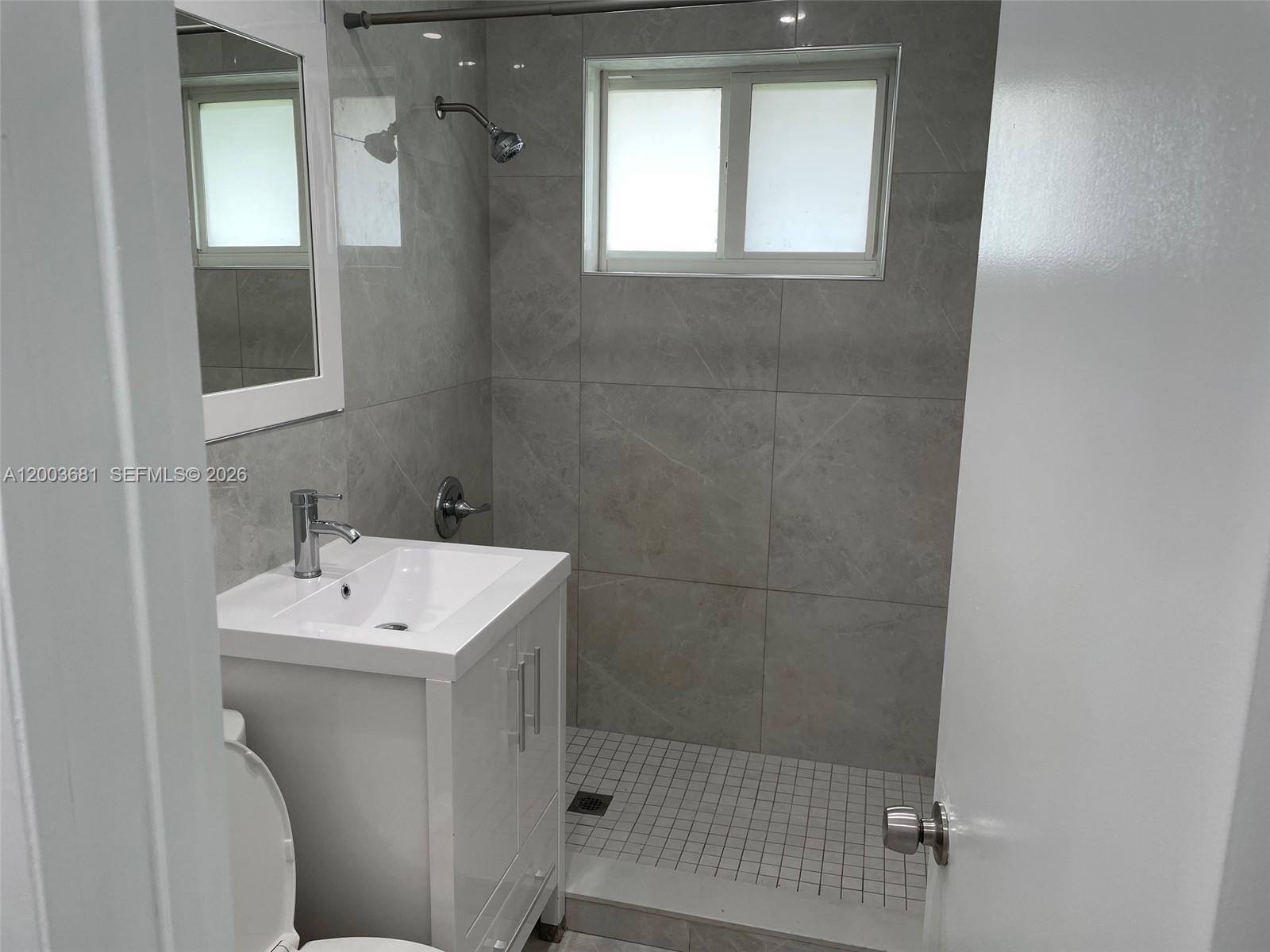 A small bathroom features a white vanity, a tiled shower stall, and a wall mirror — 8640 SW 125th Ter, Miami FL 33156, MIAMI, FL