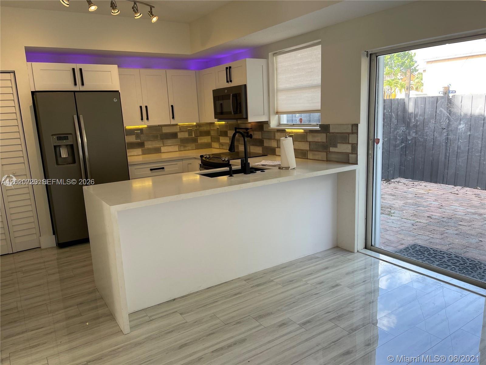 A modern kitchen features white cabinets, a quartz island, and purple accent lighting — 5200 NW 109th Ave # 1, Doral FL 33178, DORAL, FL