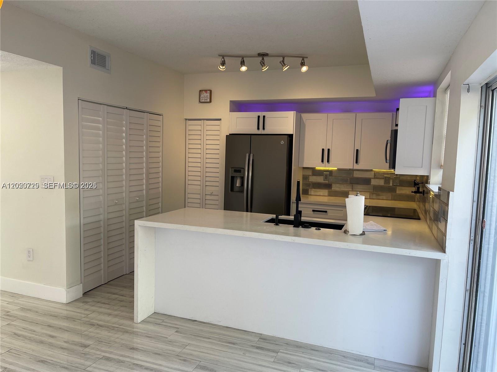 A modern kitchen features white cabinets, a quartz island, stainless steel appliances, and purple lighting — 5200 NW 109th Ave # 1, Doral FL 33178, DORAL, FL