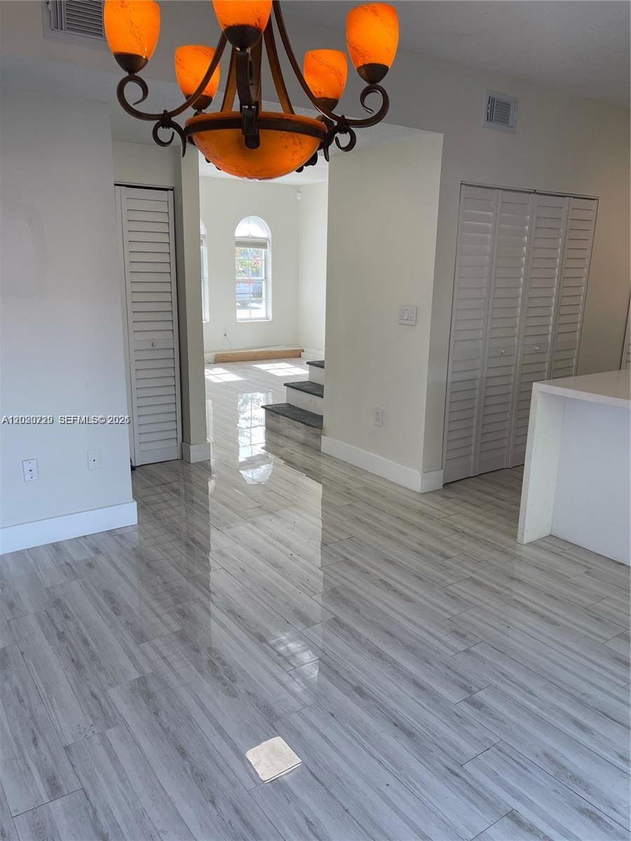 A dining area features a chandelier, light wood-look tile flooring, and white louvered closet doors — 5200 NW 109th Ave # 1, Doral FL 33178, DORAL, FL