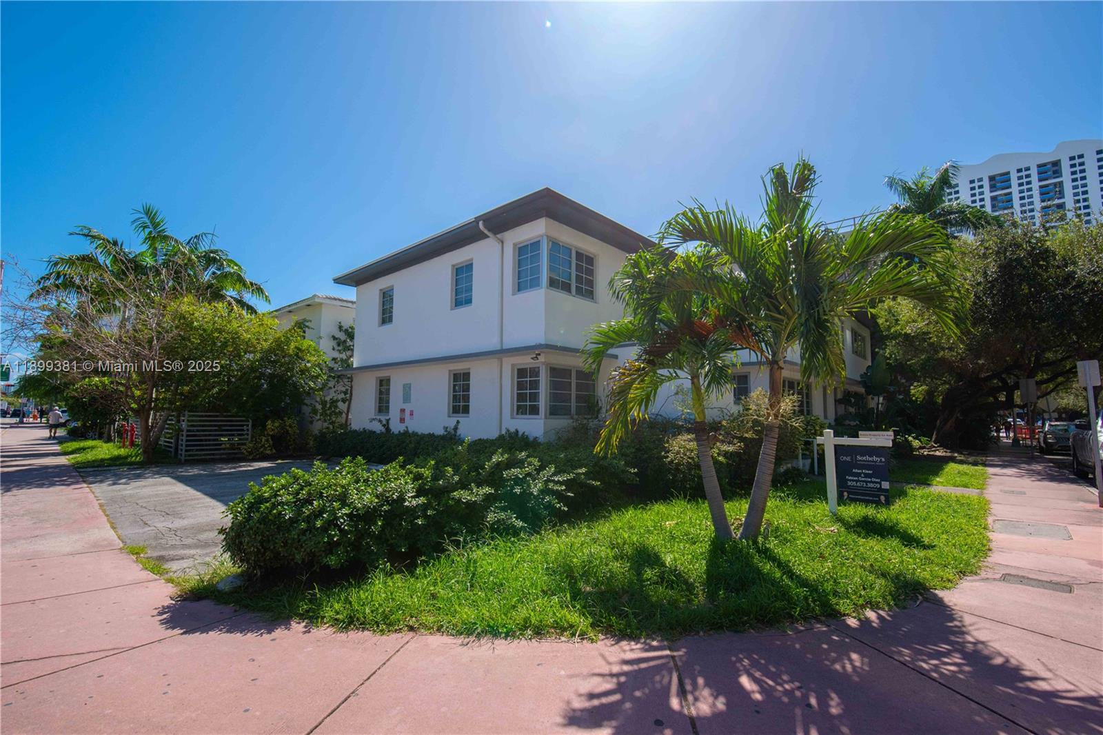 A two-story white building with a flat roof stands behind a lawn and palm trees — 1485 Bay Rd, Miami Beach FL 33139, MIAMI BEACH, FL