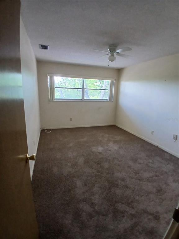 An empty bedroom features brown carpet, white walls, a ceiling fan, and a single window — 5880 38TH AVENUE N UNIT 304, ST PETERSBURG, FL