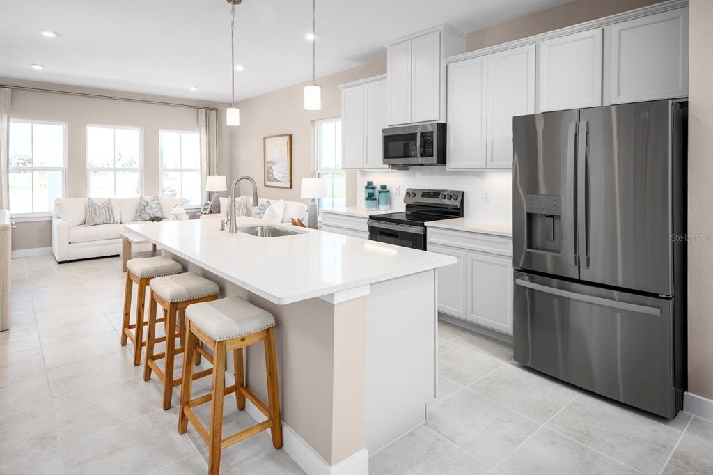 A modern kitchen with white cabinets, stainless steel appliances, and a central island with stools — 657 STONELEIGH LANE, DEBARY, FL