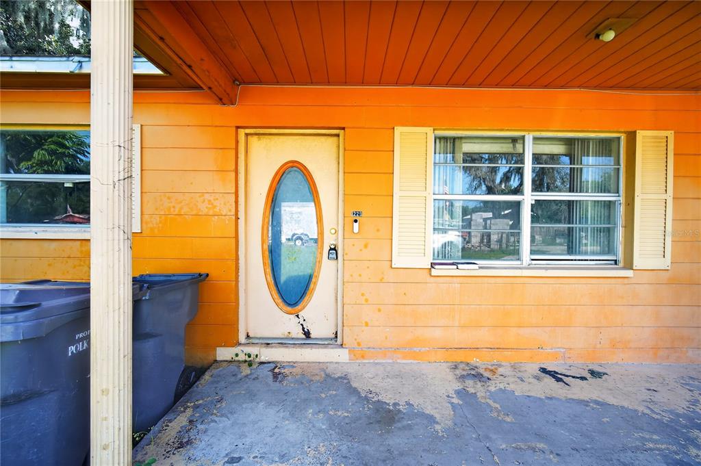 The exterior of a house features orange siding, a white front door, and a concrete porch — 1229 EL CAMINO ROAD, LAKELAND, FL