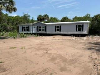 A light-colored manufactured home sits on a dirt lot surrounded by trees — 8000 NW 189TH AVENUE, OKEECHOBEE, FL