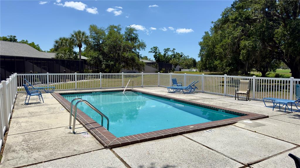 An outdoor rectangular swimming pool is surrounded by a white fence and lounge chairs — 335 BOBBY JONES ROAD UNIT 335, SARASOTA, FL