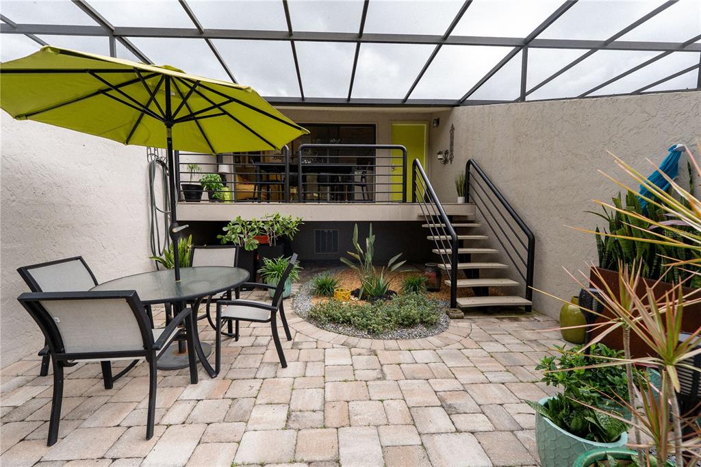 A patio with a dining set, umbrella, and stairs leading to an elevated deck — 335 BOBBY JONES ROAD UNIT 335, SARASOTA, FL