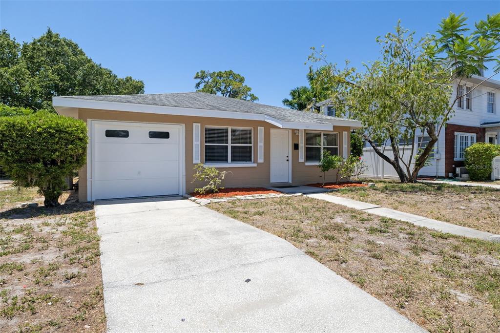 A single-story house with a tan exterior, a white garage door, and a concrete driveway — 808 26TH STREET W, BRADENTON, FL