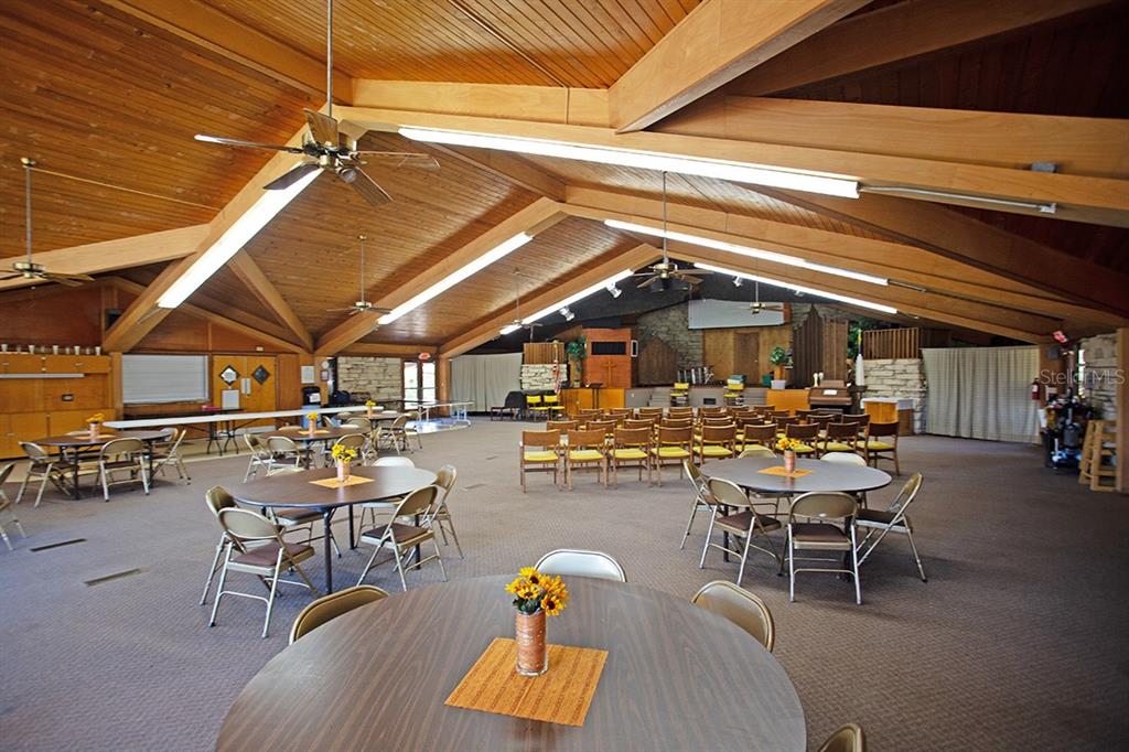 A large, open-concept community hall features a vaulted wood-paneled ceiling and round dining tables — 3115 DRYER AVENUE, LARGO, FL