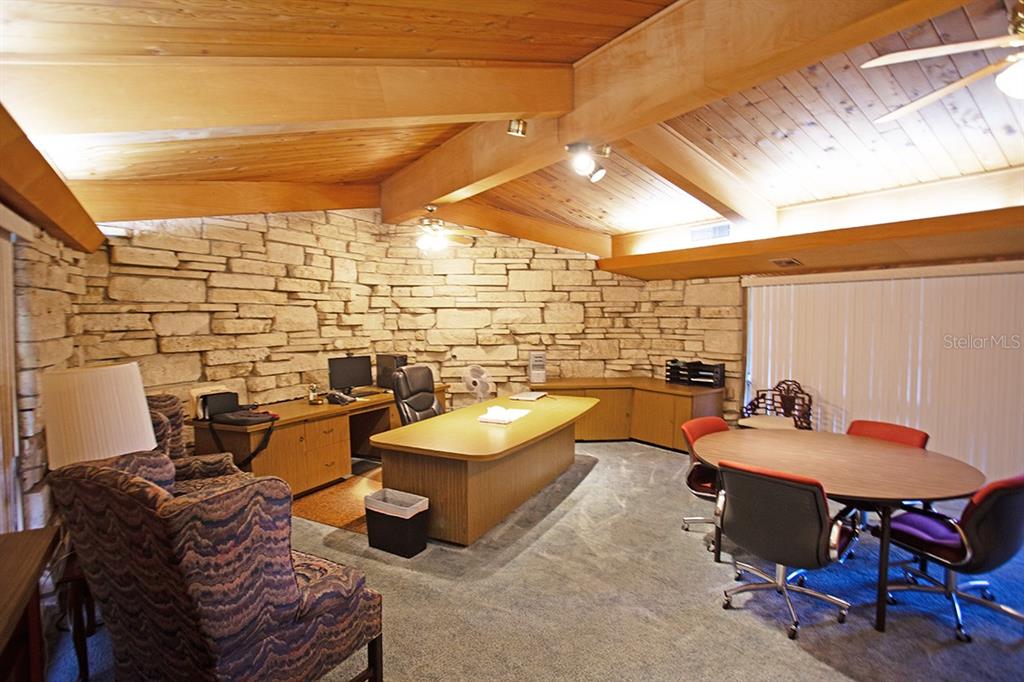 A home office features a stone wall, wood-paneled vaulted ceiling, and a large desk — 3115 DRYER AVENUE, LARGO, FL