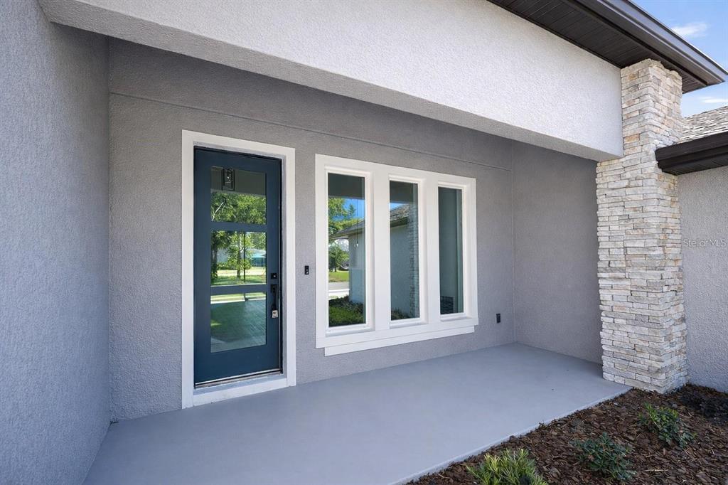 A gray stucco home exterior features a blue front door and a triple-pane window — 21 LAMAR LANE, PALM COAST, FL