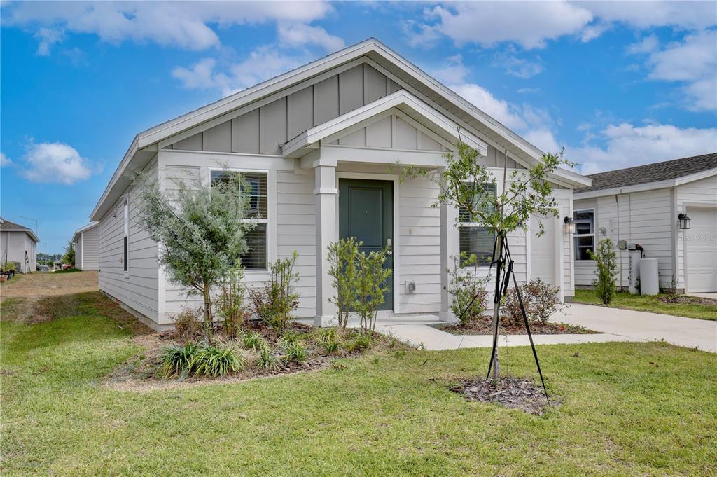A one-story house with light-colored siding, a dark front door, and a small front porch — 1709 TEAGAN LANE, WINTER HAVEN, FL